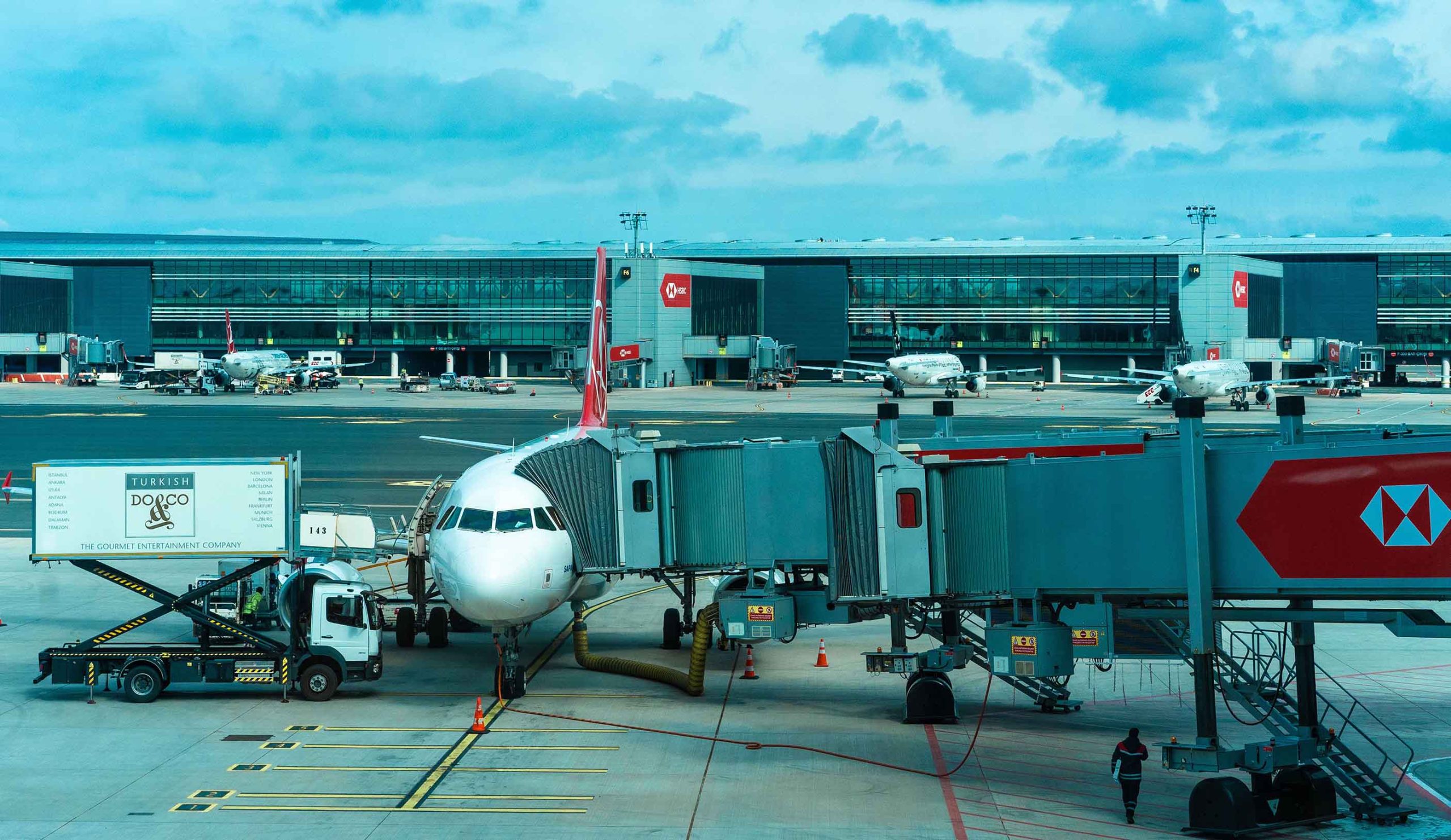 A commercial airplane parked at an airport terminal, with passengers boarding and luggage being loaded A commercial airplane parked at an airport terminal, with passengers boarding and luggage being loaded