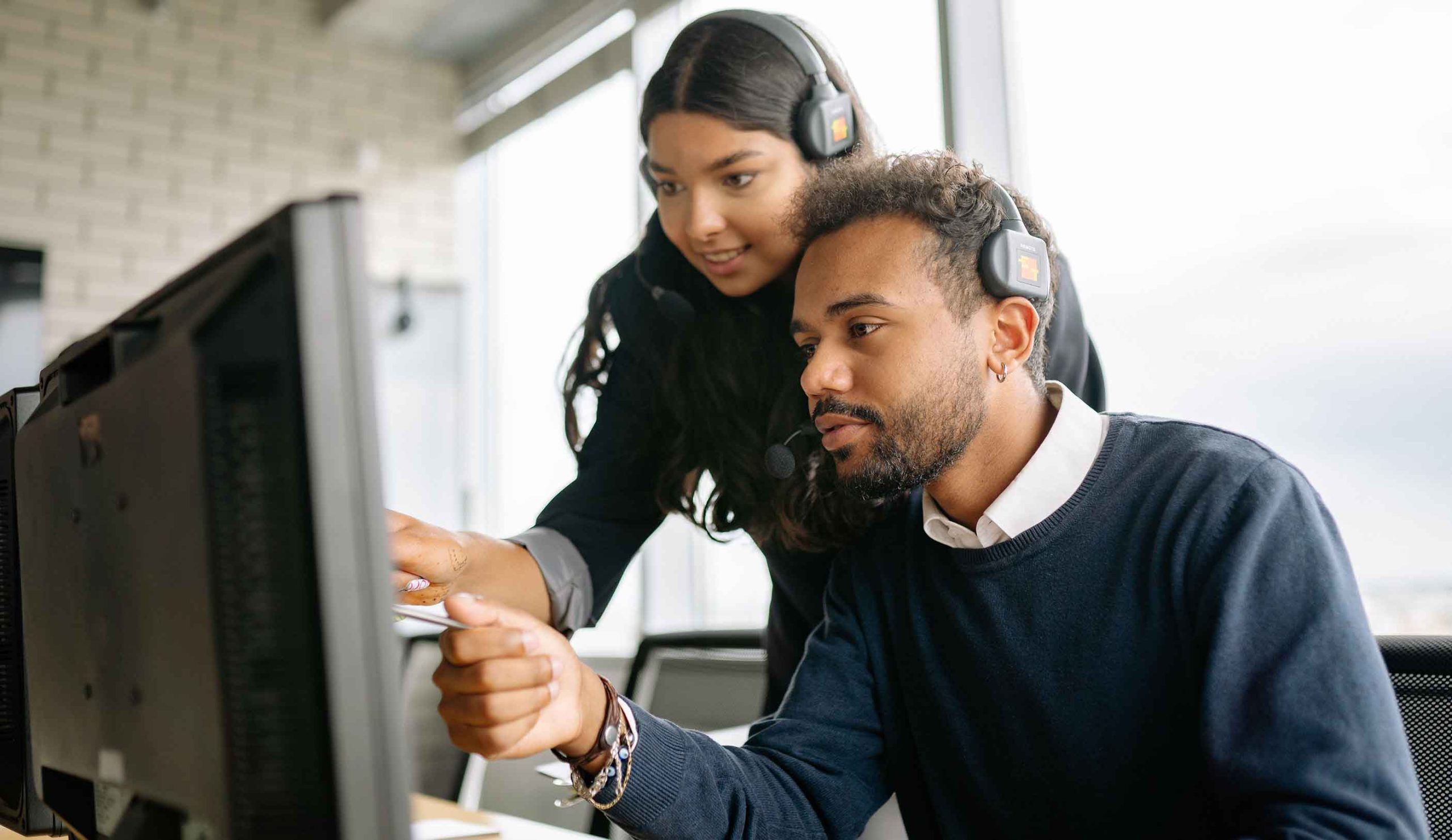 A man and woman collaborating on a computer, focused on their work in a modern office setting