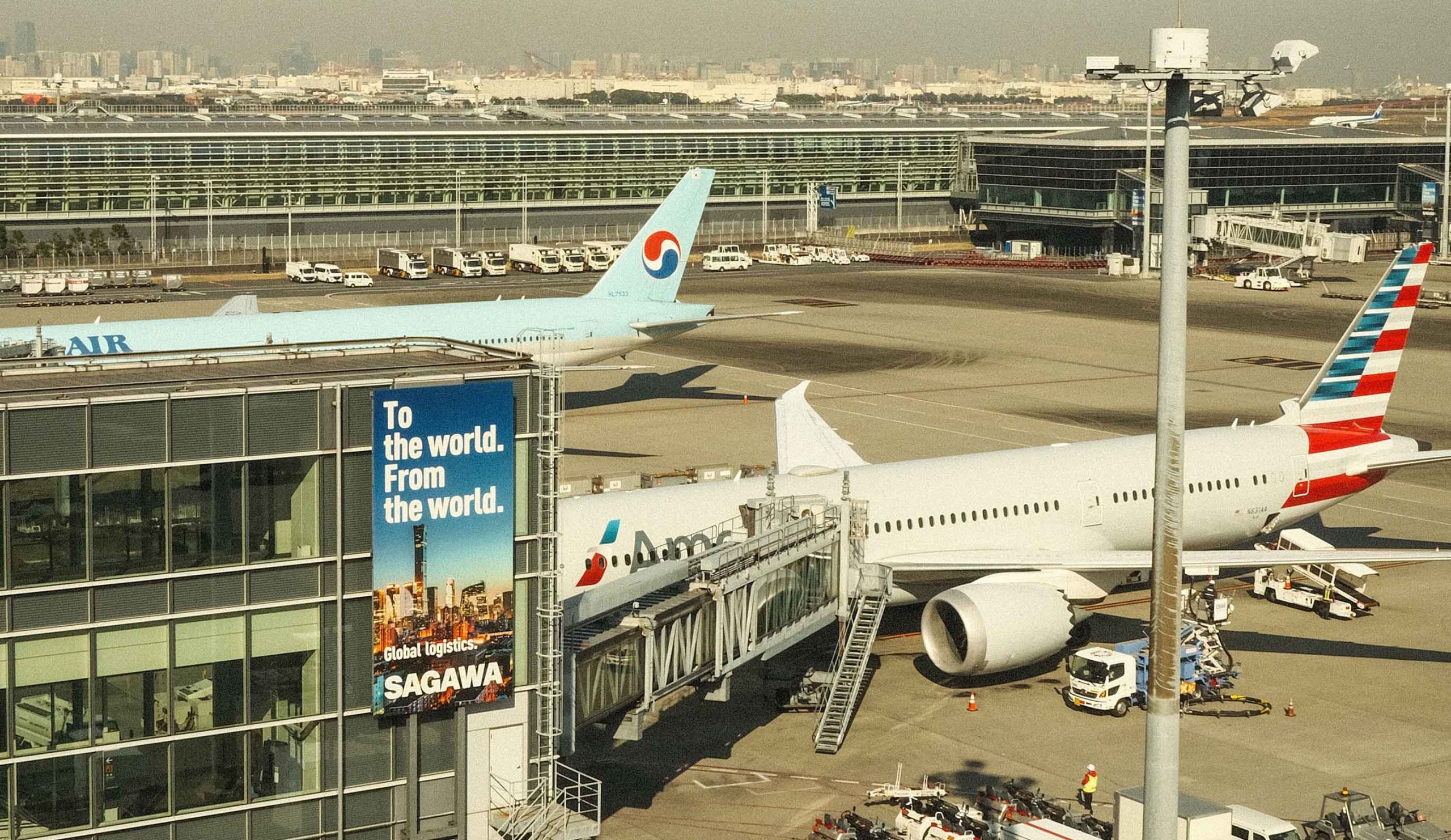 A large airplane parked on the tarmac at an airport, with terminal buildings visible in the background.