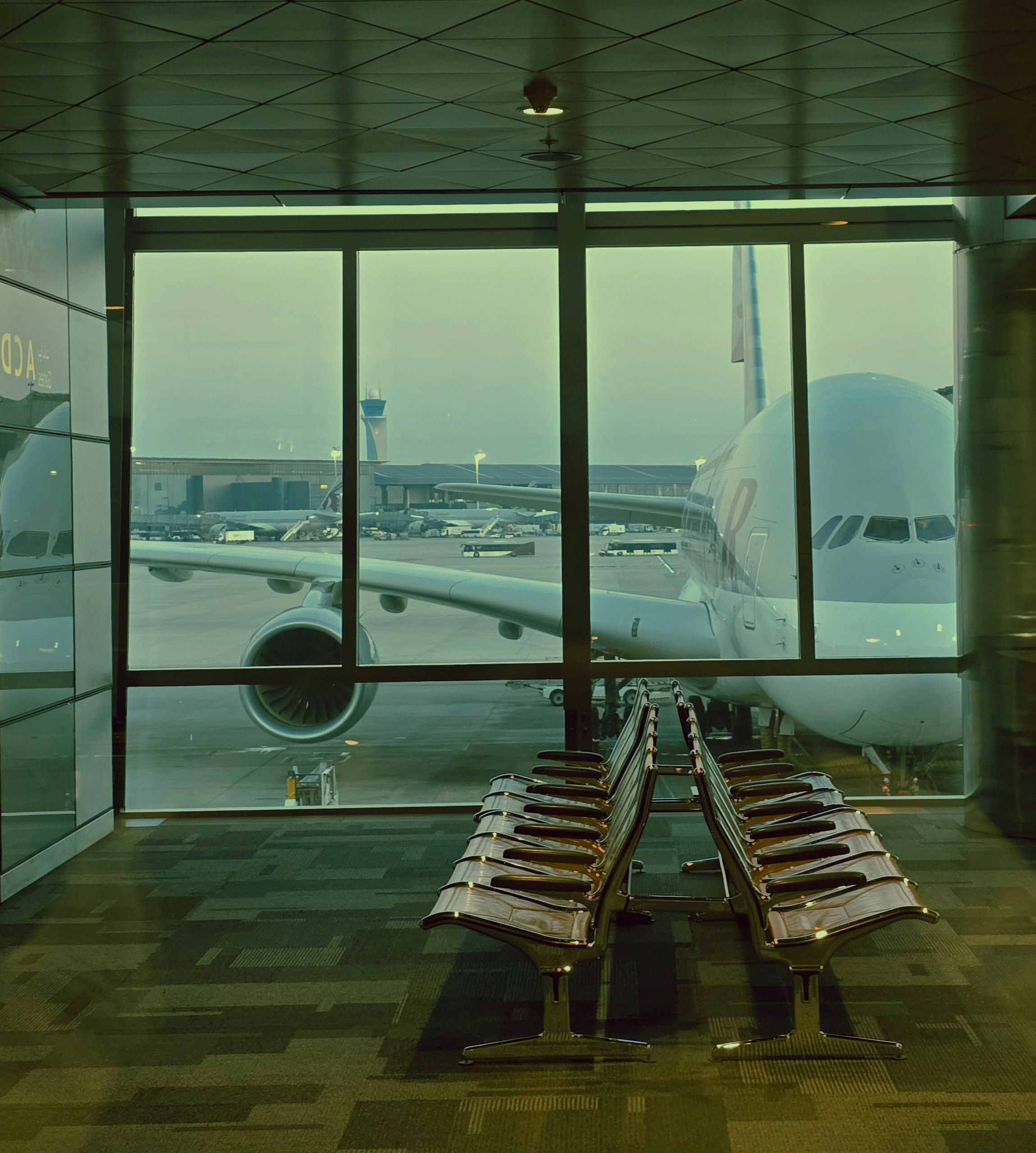 A large airplane parked at an airport, with terminal buildings and runway visible in the background.
